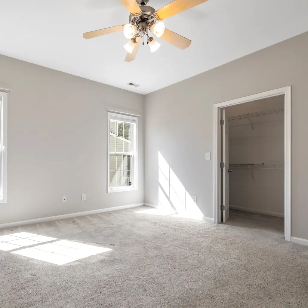 Empty bedroom with light grey carpet, window and open closet